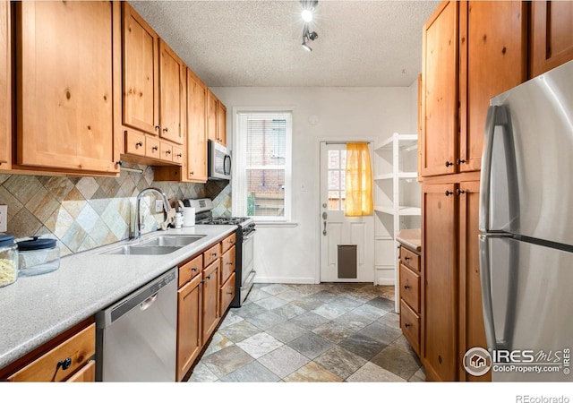 135 E 8th Ave, Denver, CO 80203 - kitchen featuring appliances with stainless steel finishes, a sink, a textured ceiling, tasteful backsplash, and baseboards