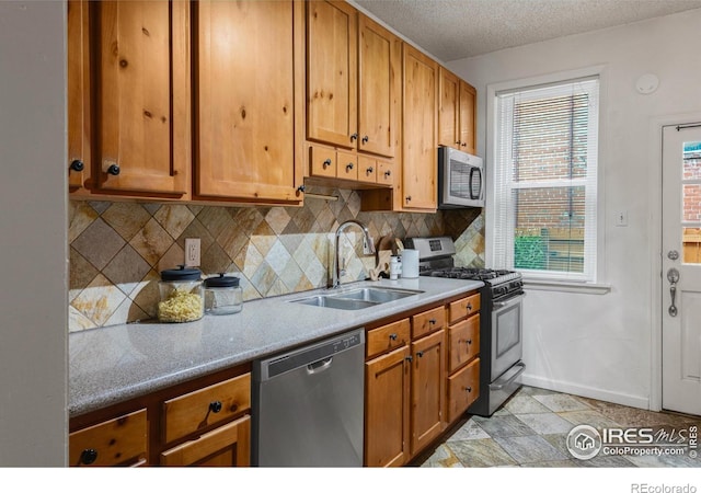135 E 8th Ave, Denver, CO 80203 - kitchen featuring stainless steel appliances, a sink, tasteful backsplash, a textured ceiling, and brown cabinets