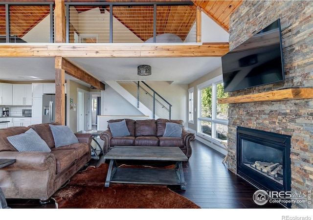 61 County Road 8501, Tabernash, CO 80478 - living room featuring dark wood finished floors, high vaulted ceiling, stairs, a stone fireplace, and a baseboard radiator