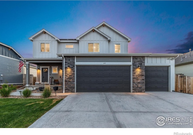 1495 S Sunfield Dr, Milliken, CO 80543 - view of front facade with board and batten siding, driveway, stone siding, and a garage