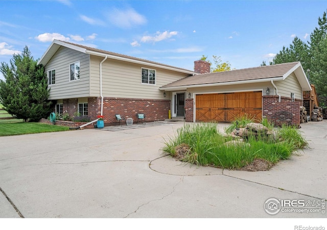 1921 Glenview Ct, Berthoud, CO 80513 - split level home with brick siding, a chimney, a garage, and driveway