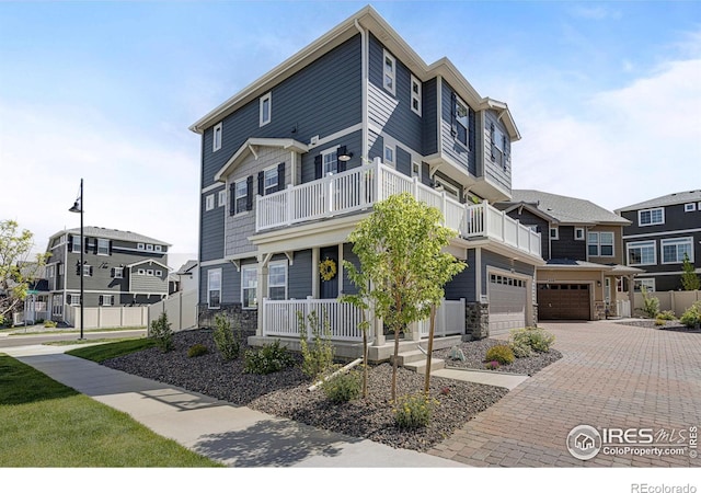542 Highlands Cir, Erie, CO 80516 - view of front facade with a balcony, an attached garage, covered porch, decorative driveway, and stone siding