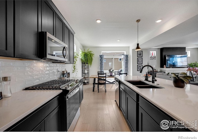542 Highlands Cir, Erie, CO 80516 - kitchen featuring appliances with stainless steel finishes, dark cabinets, light countertops, light wood-style flooring, and recessed lighting