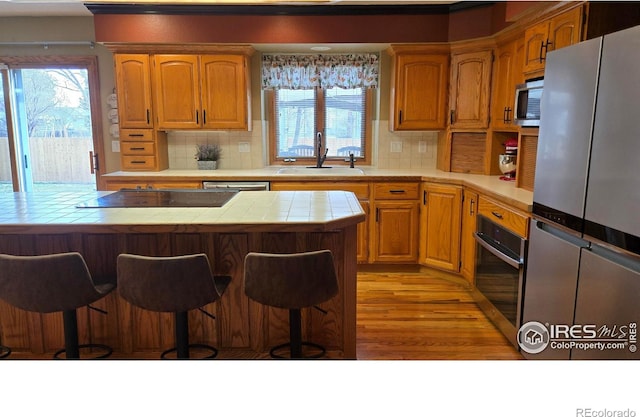 2152 45th Ave, Greeley, CO 80634 - kitchen featuring stainless steel appliances, tile countertops, a sink, and a kitchen bar