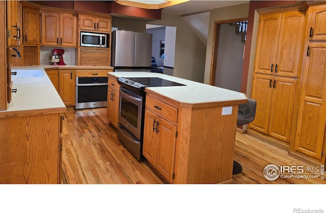2152 45th Ave, Greeley, CO 80634 - kitchen with appliances with stainless steel finishes, a sink, a center island, light countertops, and light wood-style floors