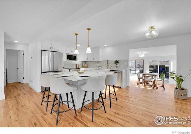 4642 Everett Ct, Wheat Ridge, CO 80033 - kitchen featuring appliances with stainless steel finishes, tasteful backsplash, light wood-type flooring, a breakfast bar, and recessed lighting