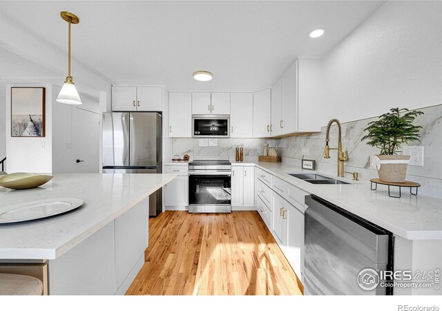 4642 Everett Ct, Wheat Ridge, CO 80033 - kitchen featuring stainless steel appliances, a sink, white cabinets, tasteful backsplash, and hanging light fixtures