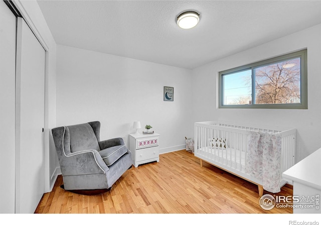 4642 Everett Ct, Wheat Ridge, CO 80033 - bedroom with wood finished floors, a closet, baseboards, a textured ceiling, and a crib