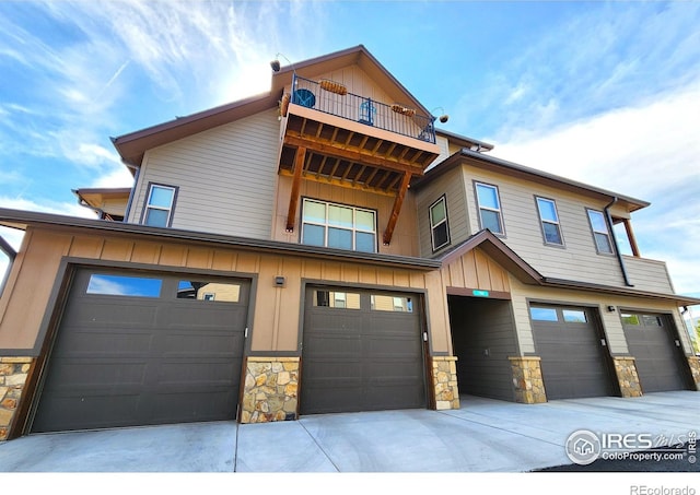 1768 Wildfire Rd Unit 101, Estes Park, CO 80517 - townhome / multi-family property featuring stone siding, a balcony, a garage, board and batten siding, and concrete driveway