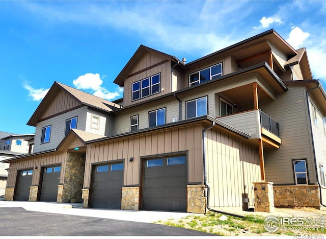 1768 Wildfire Rd Unit 101, Estes Park, CO 80517 - view of front facade featuring an attached garage, stone siding, a balcony, and board and batten siding