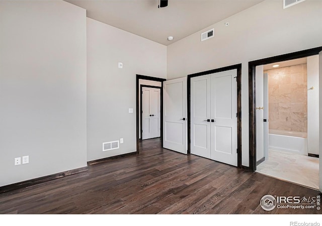 1768 Wildfire Rd Unit 101, Estes Park, CO 80517 - unfurnished bedroom with dark wood-type flooring, baseboards, ensuite bath, a closet, and a towering ceiling