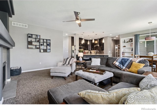 2620 Brush Creek Dr, Fort Collins, CO 80528 - carpeted living area featuring a ceiling fan, a tiled fireplace, baseboards, recessed lighting, and a sink