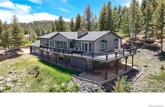 1100 Deer Trail Rd, Boulder, CO 80302 - back of house with a wooden deck, a chimney, a forest view, and a patio