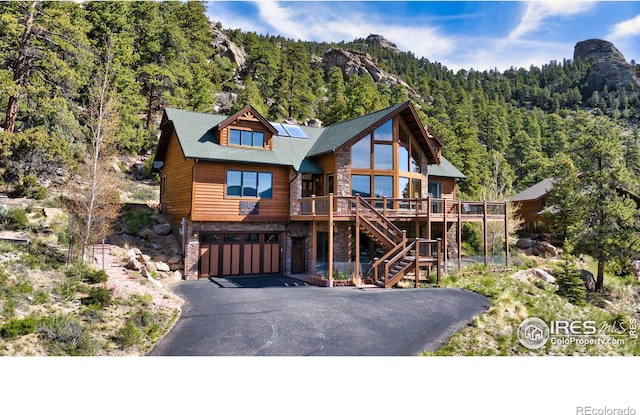 303 Curry Dr, Estes Park, CO 80517 - view of front of home with stone siding, a wooded view, driveway, stairway, and an attached garage