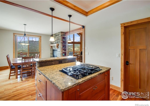 303 Curry Dr, Estes Park, CO 80517 - kitchen with black gas stovetop, light wood finished floors, a stone fireplace, and healthy amount of natural light