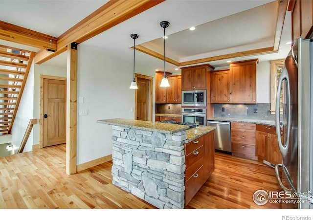 303 Curry Dr, Estes Park, CO 80517 - kitchen featuring stainless steel appliances, a tray ceiling, decorative backsplash, light wood-style floors, and light stone countertops