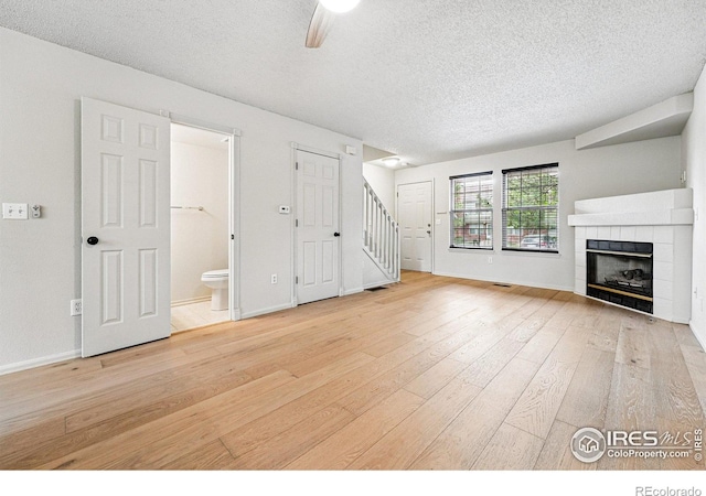 3022 W 107th Pl Unit D, Westminster, CO 80031 - unfurnished living room with a textured ceiling, light wood-type flooring, stairs, a fireplace, and baseboards