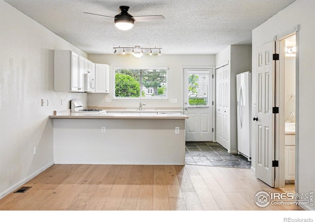 3022 W 107th Pl Unit D, Westminster, CO 80031 - kitchen with a peninsula, white appliances, light wood-style floors, light countertops, and a textured ceiling