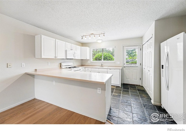3022 W 107th Pl Unit D, Westminster, CO 80031 - kitchen with white appliances, a peninsula, light countertops, a sink, and white cabinetry