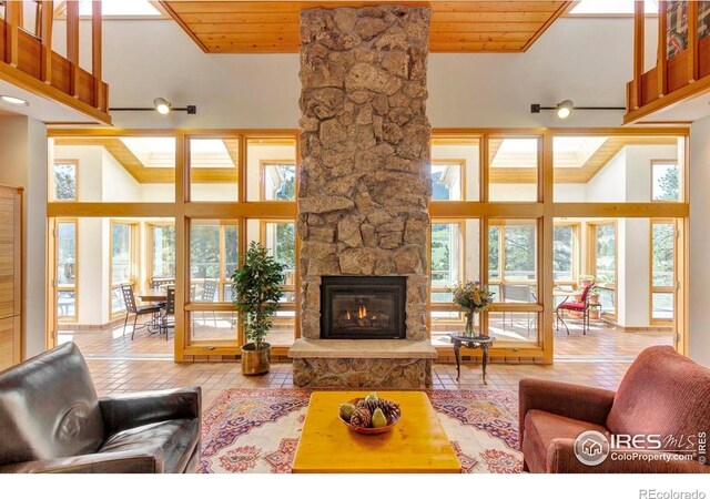 125 Saddleback Ln, Estes Park, CO 80517 - tiled living area with wood ceiling, a fireplace, and a high ceiling