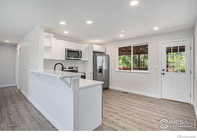 15904 E Bates Pl, Aurora, CO 80013 - kitchen featuring stainless steel appliances, open shelves, light countertops, light wood-type flooring, and recessed lighting