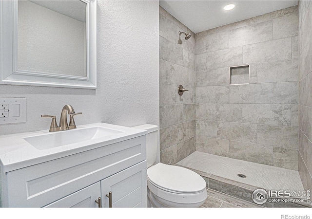 15904 E Bates Pl, Aurora, CO 80013 - bathroom featuring tiled shower, toilet, vanity, recessed lighting, and a textured wall