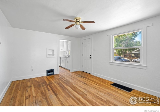 618 16th St, Greeley, CO 80631 - unfurnished living room with ceiling fan, light wood-style floors, a sink, and baseboards