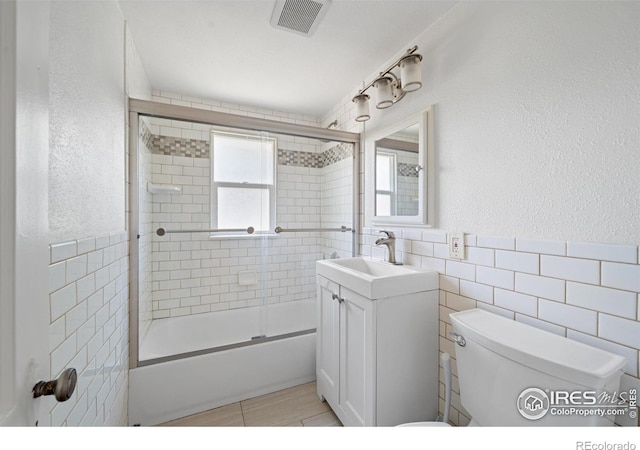 618 16th St, Greeley, CO 80631 - bathroom with tile walls, toilet, vanity, shower / bath combination with glass door, and a textured wall