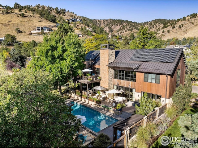 3737 Spring Valley Rd, Boulder, CO 80304 - rear view of property with a standing seam roof, a chimney, a balcony, metal roof, and an outdoor pool