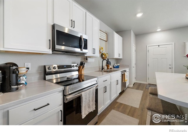 253 Molinar St, Johnstown, CO 80534 - kitchen featuring appliances with stainless steel finishes, a sink, white cabinetry, wood finished floors, and recessed lighting