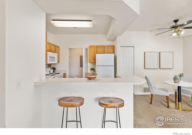 4545 Wheaton Dr Unit A-290, Fort Collins, CO 80525 - kitchen with white appliances, a kitchen bar, a peninsula, and light countertops