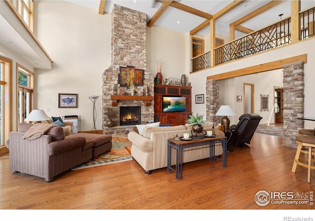 5025 Eagle Lake Dr, Fort Collins, CO 80524 - living room with a towering ceiling, light wood-style floors, a stone fireplace, and beamed ceiling