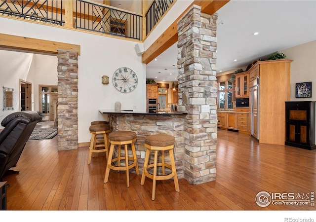 5025 Eagle Lake Dr, Fort Collins, CO 80524 - indoor bar featuring ornate columns, paneled built in refrigerator, light wood-type flooring, a towering ceiling, and oven