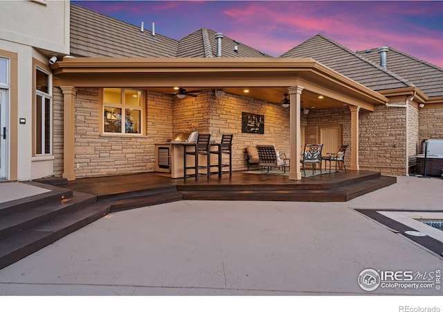5025 Eagle Lake Dr, Fort Collins, CO 80524 - back of property at dusk featuring stone siding, a ceiling fan, a wooden deck, and a patio area