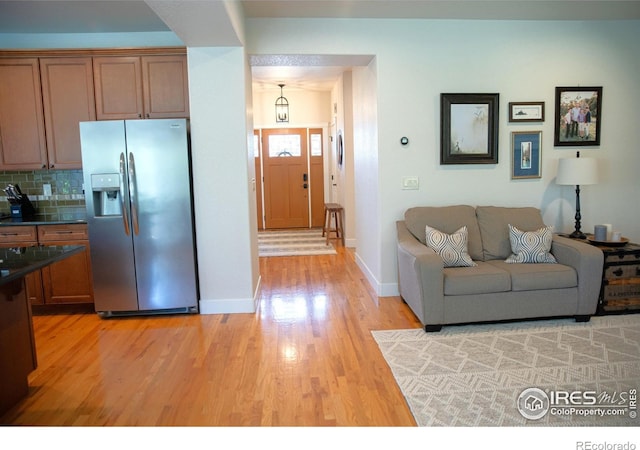 6523 Spanish Bay Dr, Windsor, CO 80550 - kitchen with stainless steel fridge, light wood-type flooring, dark countertops, baseboards, and brown cabinetry
