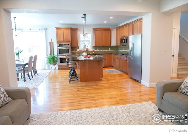 6523 Spanish Bay Dr, Windsor, CO 80550 - kitchen with appliances with stainless steel finishes, open floor plan, a kitchen breakfast bar, light wood-style flooring, and recessed lighting