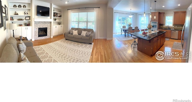 6523 Spanish Bay Dr, Windsor, CO 80550 - living area featuring healthy amount of natural light, light wood finished floors, a tiled fireplace, and baseboards