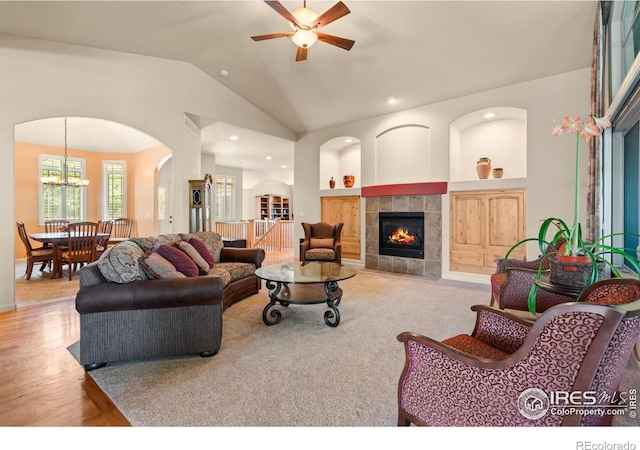 6535 Half Moon Bay Dr, Windsor, CO 80550 - living room with a ceiling fan, a fireplace, arched walkways, vaulted ceiling, and a chandelier