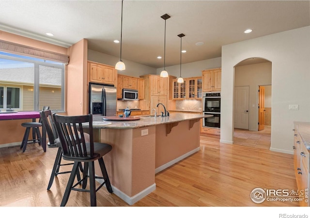 6535 Half Moon Bay Dr, Windsor, CO 80550 - kitchen featuring stainless steel appliances, a kitchen bar, light wood finished floors, a sink, and glass insert cabinets