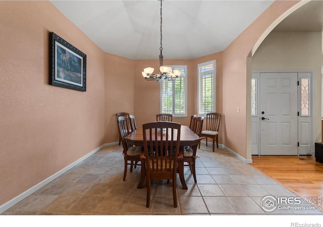 6535 Half Moon Bay Dr, Windsor, CO 80550 - dining area with arched walkways, a chandelier, baseboards, and light tile patterned floors