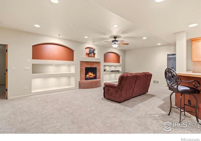 6535 Half Moon Bay Dr, Windsor, CO 80550 - living area with recessed lighting, built in shelves, light colored carpet, a tiled fireplace, and ceiling fan