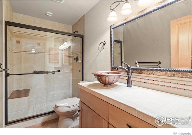 6535 Half Moon Bay Dr, Windsor, CO 80550 - full bath with a textured wall, toilet, vanity, a shower stall, and tile patterned flooring