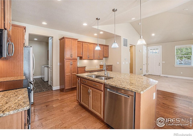 4751 Pleasant Oak Dr Unit B44, Fort Collins, CO 80525 - kitchen featuring appliances with stainless steel finishes, a sink, washer and clothes dryer, light wood-type flooring, and vaulted ceiling