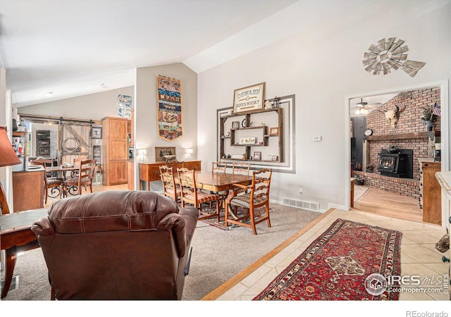 3412 Erving Ct, Berthoud, CO 80513 - living area with a wood stove, a barn door, light tile patterned floors, high vaulted ceiling, and baseboards