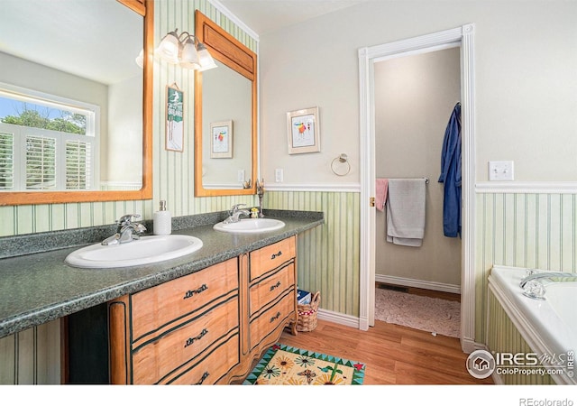 3412 Erving Ct, Berthoud, CO 80513 - bathroom with wood finished floors, double vanity, wallpapered walls, a bath, and wainscoting