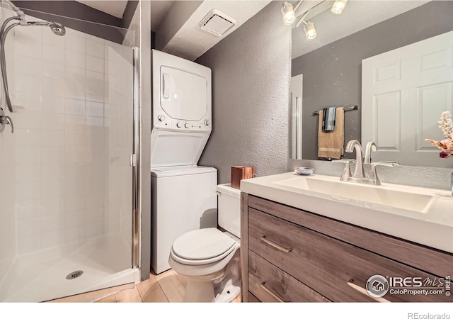855 W Moorhead Cir Unit C, Boulder, CO 80305 - bathroom with stacked washer / dryer, a stall shower, a textured wall, vanity, and toilet