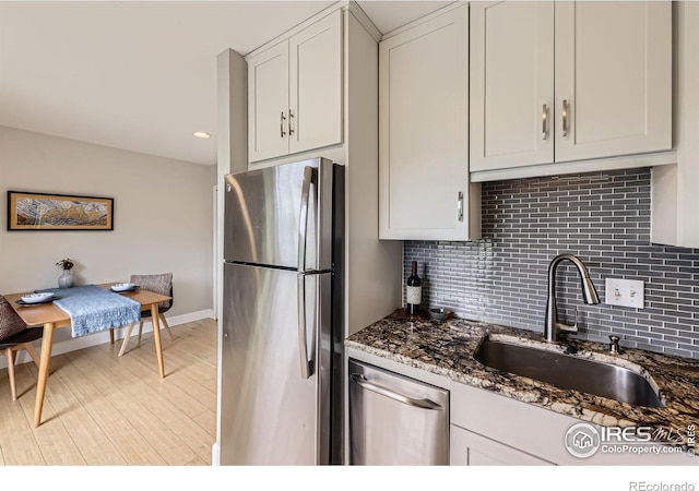 855 W Moorhead Cir Unit C, Boulder, CO 80305 - kitchen featuring appliances with stainless steel finishes, a sink, light wood-style floors, tasteful backsplash, and dark stone countertops