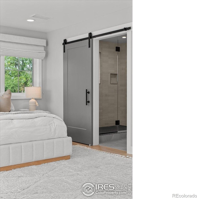 3256 S Corona St, Englewood, CO 80113 - bedroom featuring a barn door, wood finished floors, and ensuite bath