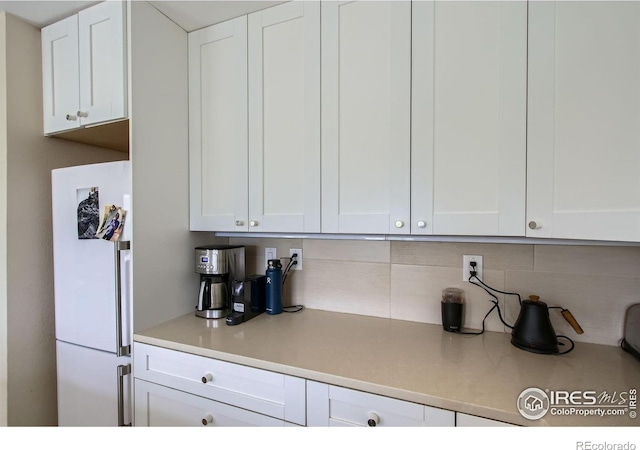 2938 Kalmia Ave Unit 26, Boulder, CO 80301 - kitchen with freestanding refrigerator, white cabinetry, decorative backsplash, and light countertops