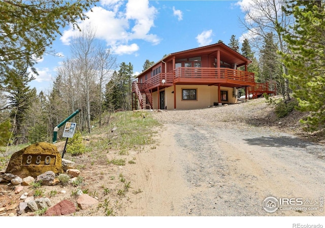 880 Hummer Dr, Nederland, CO 80466 - view of front facade with dirt driveway, a wooden deck, and stairway